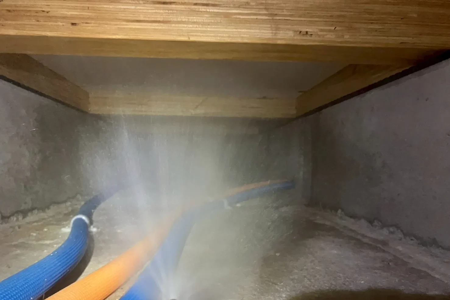 床下防蟻メンテナンス中の様子。高圧噴霧器から薬剤を霧状に放射し、基礎の隅々までバリアを形成する作業風景