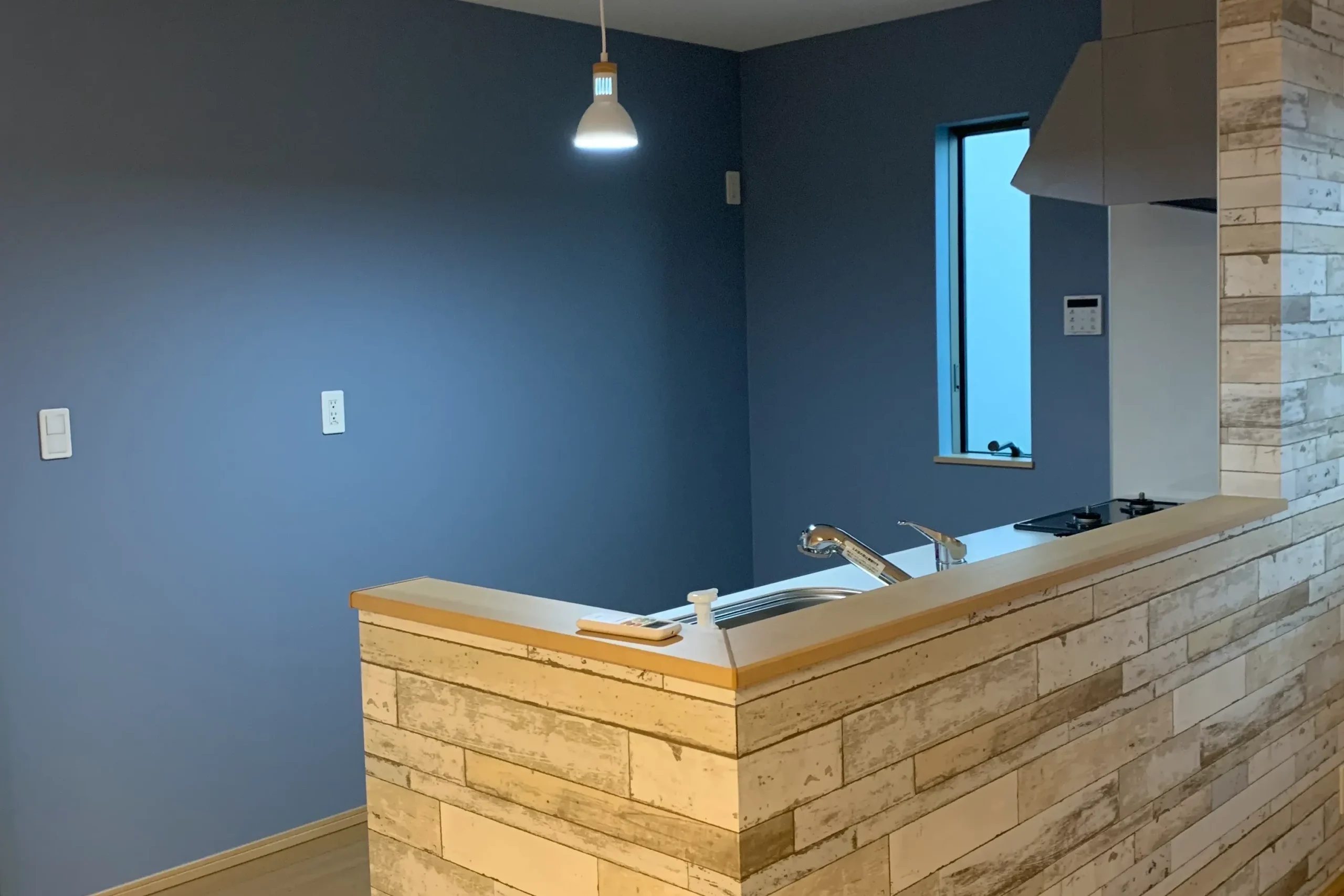 群馬県渋川市の戸建て住宅にて、キッチン奥の壁紙が、鮮やかなブルーに貼り替えられた様子。