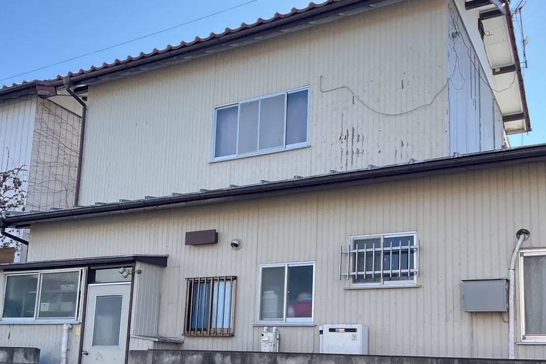 全体的に色あせと汚れが目立つ淡いベージュの外壁。