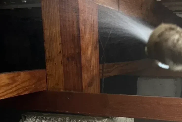 床下の木材(大引・束柱)へシロアリ駆除の薬剤を高圧散布する様子