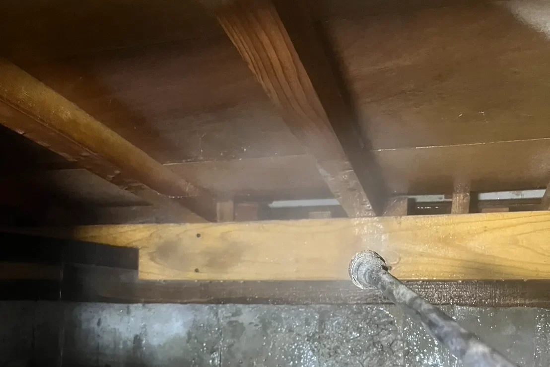 建物を支える床下の木部へ、シロアリ駆除・予防薬剤を噴霧する様子