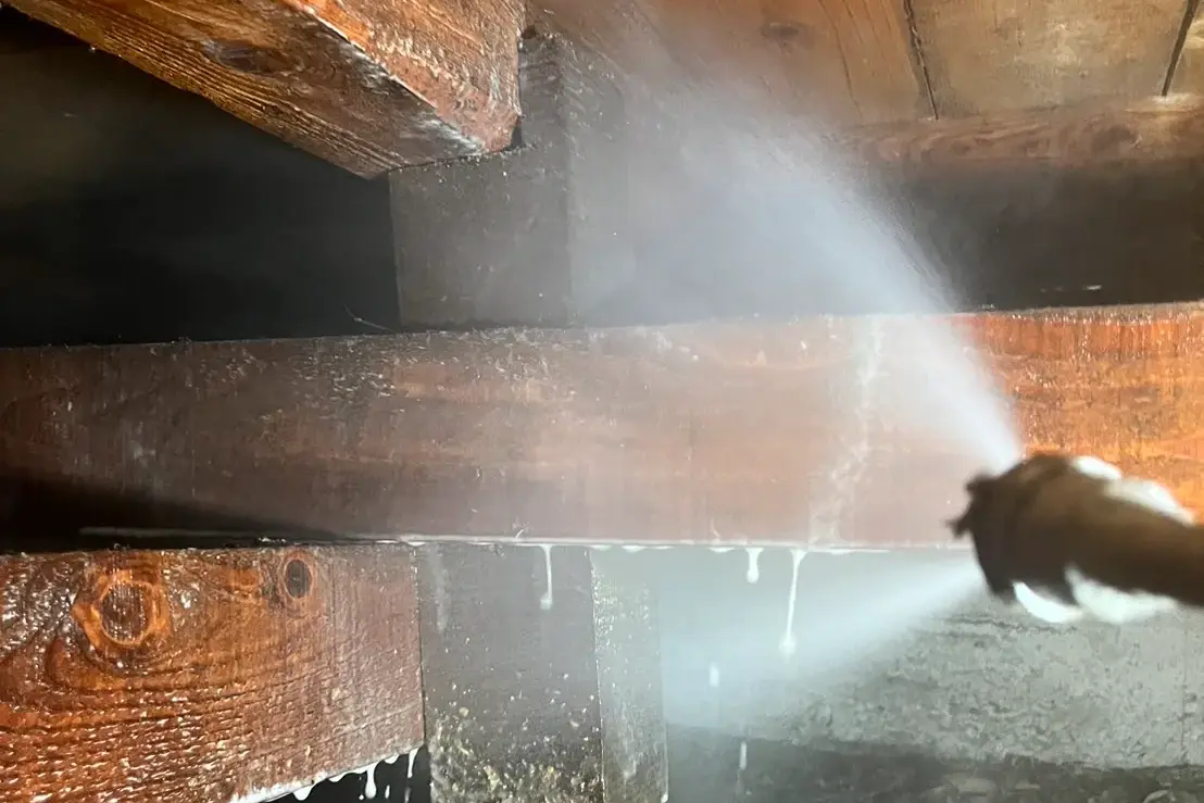 床下の木材（土台・大引き）へシロアリ予防薬剤を高圧散布している様子