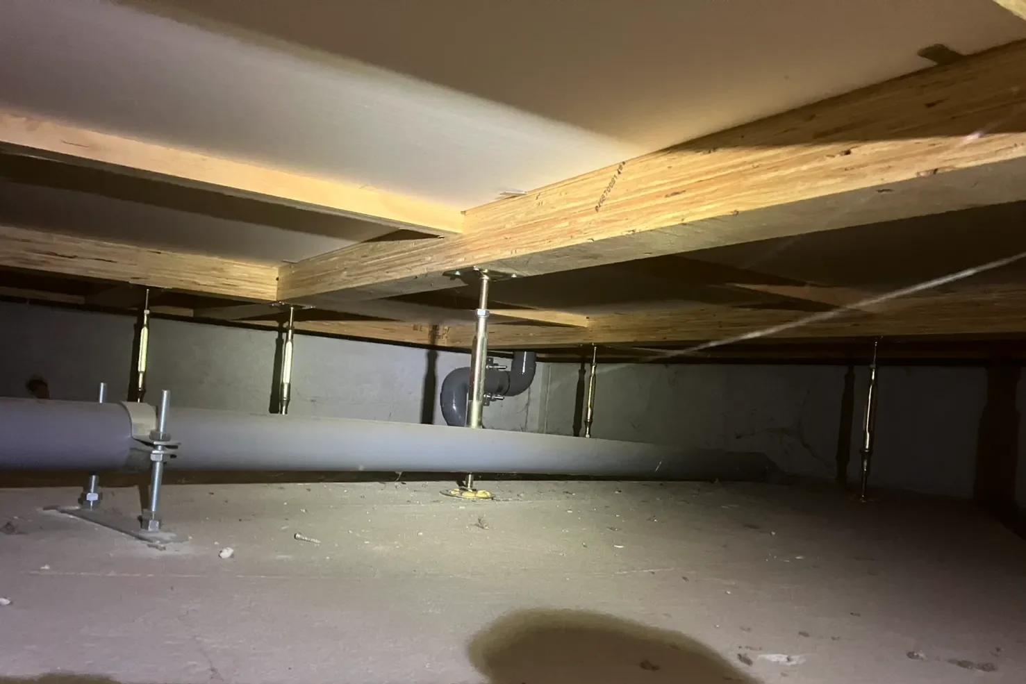 木造住宅の床下構造。鋼製束とグレーの配管が並ぶ。