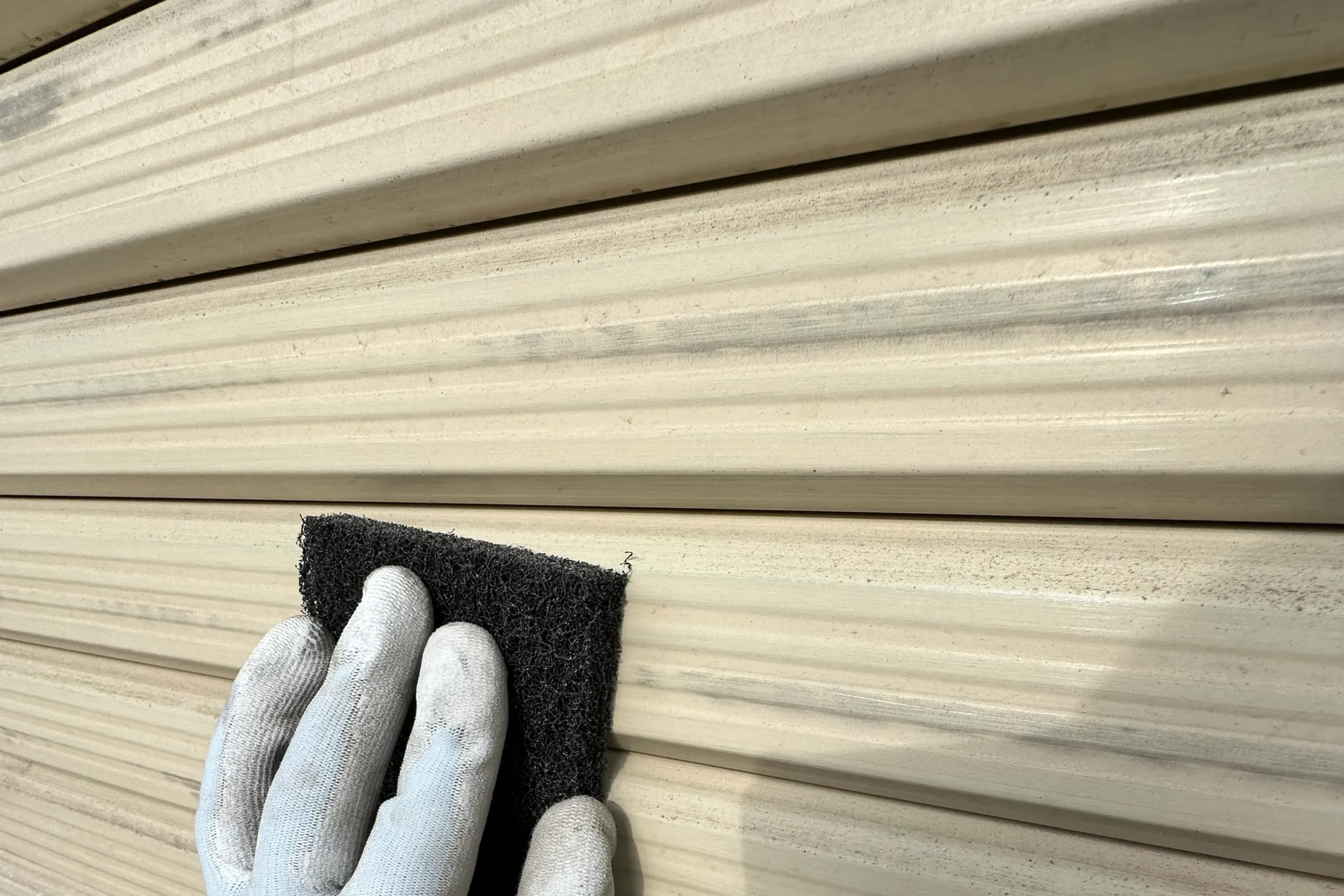 不織布研磨材を使い手作業でシャッター表面を研磨するケレン作業の様子