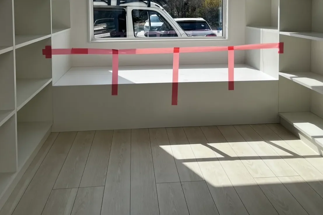 完成した壁面本棚。窓を中心に左右対称の棚が並び、中央の窓下には読書用ベンチが備わっている。