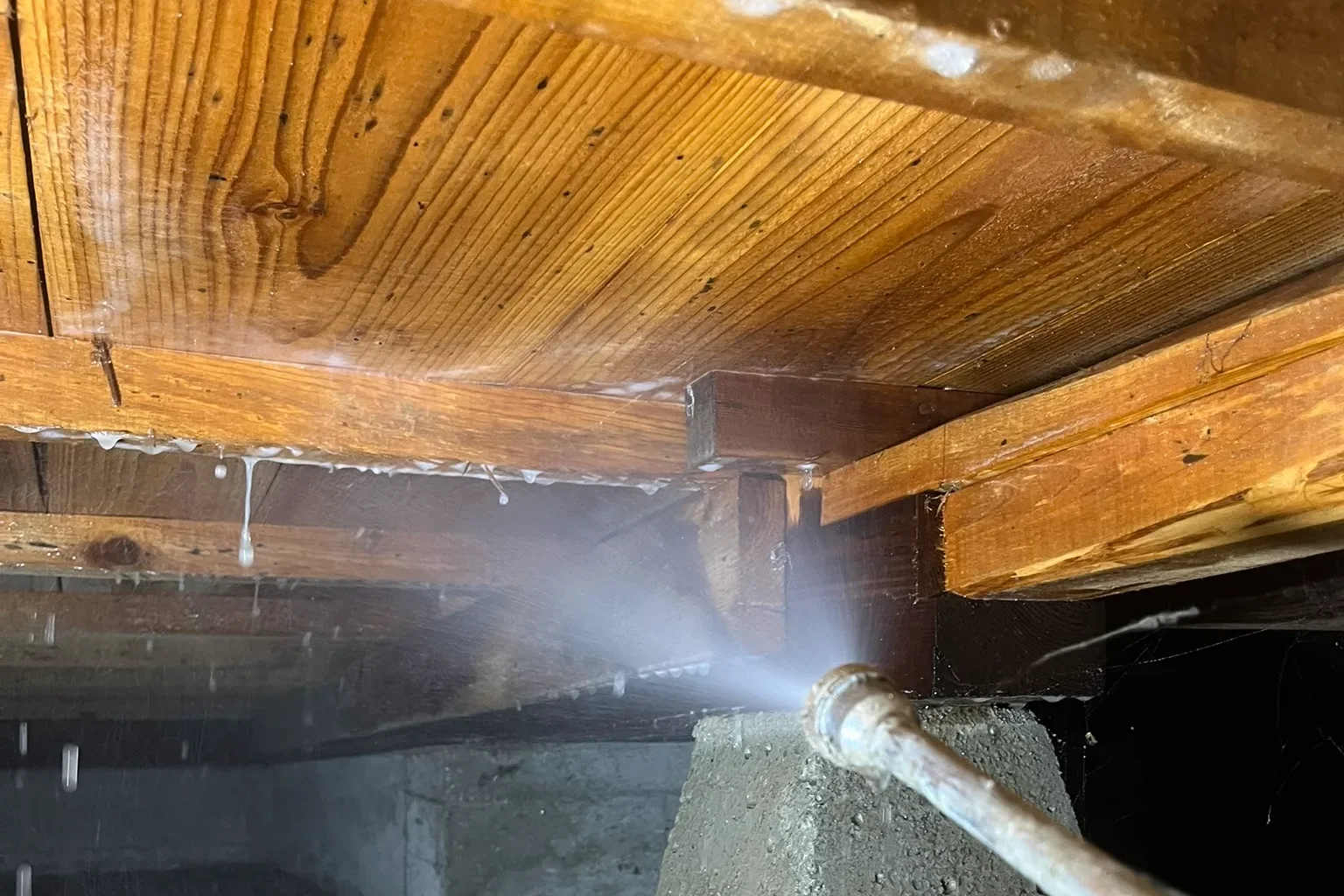 鹿児島市の築30年住宅にて、床下の土台や木材の接合部にシロアリ駆除剤を丁寧に散布している様子