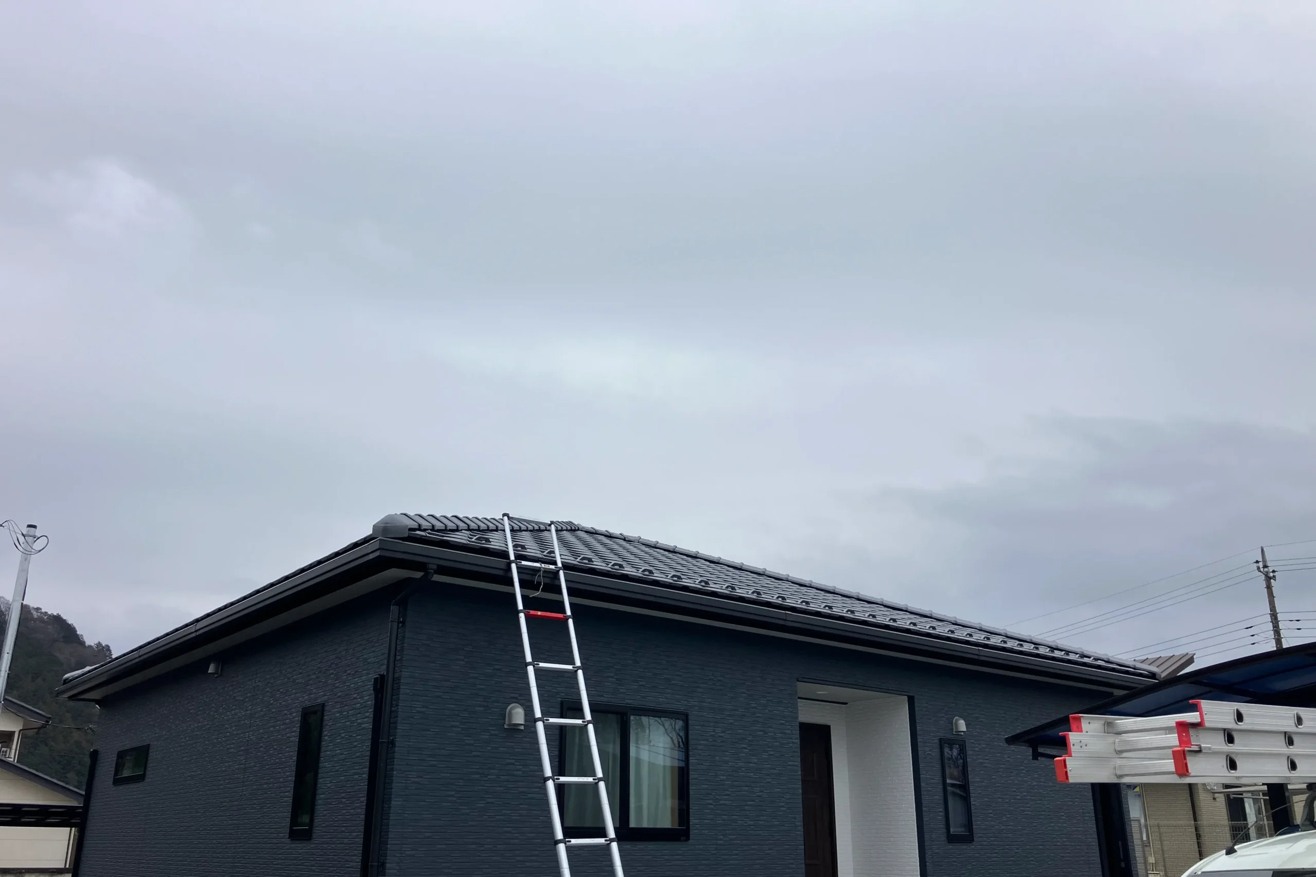 屋根上での電波調査を行うため高所作業用はしごを設置。周囲の障害物を確認し、最適なアンテナ設置場所を特定する準備段階。