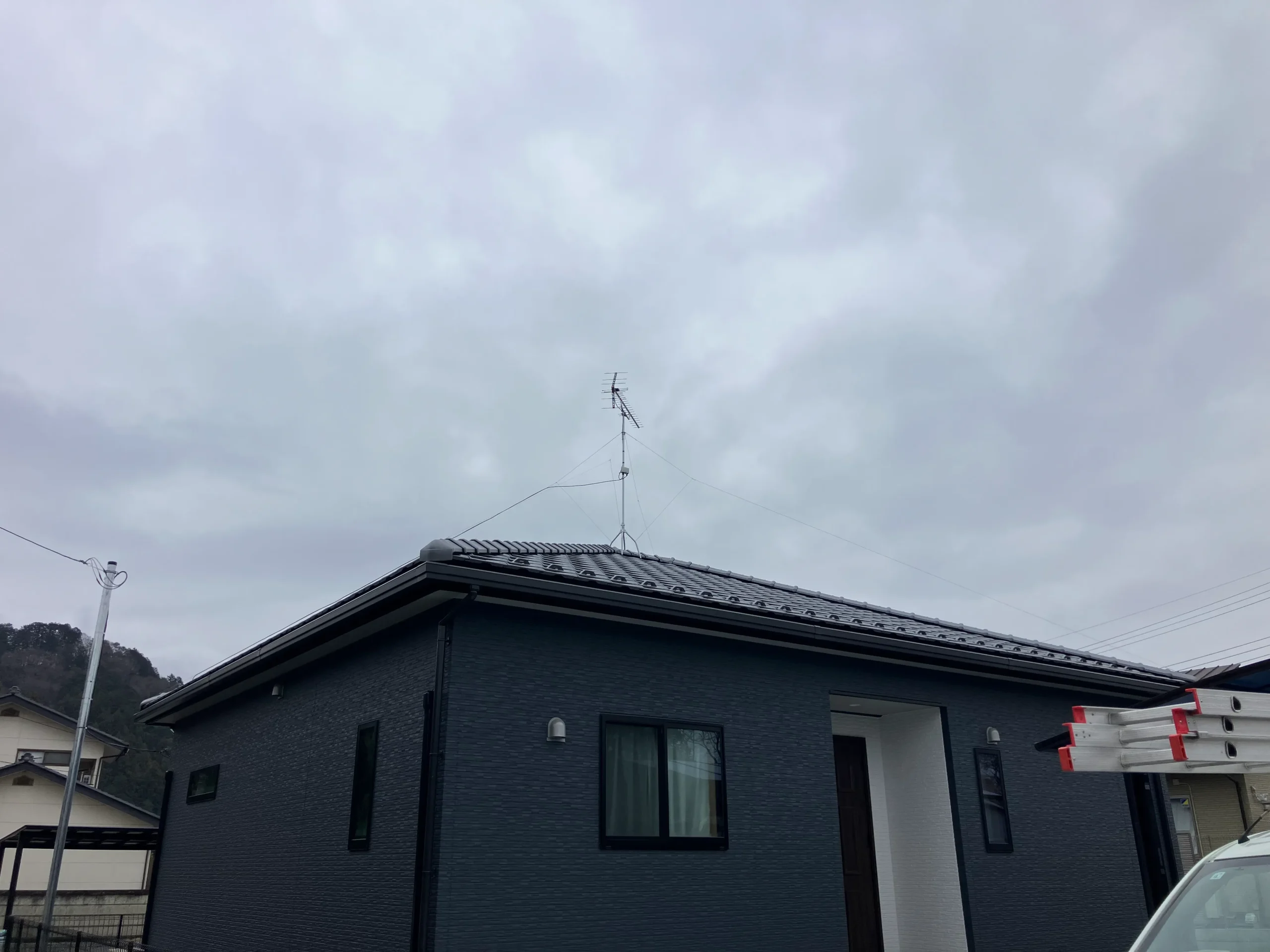 黒い外壁の洗練された外観を損なわずに、屋根上で高さを確保して安定した受信環境を実現。月々のテレビ視聴固定費をカット。