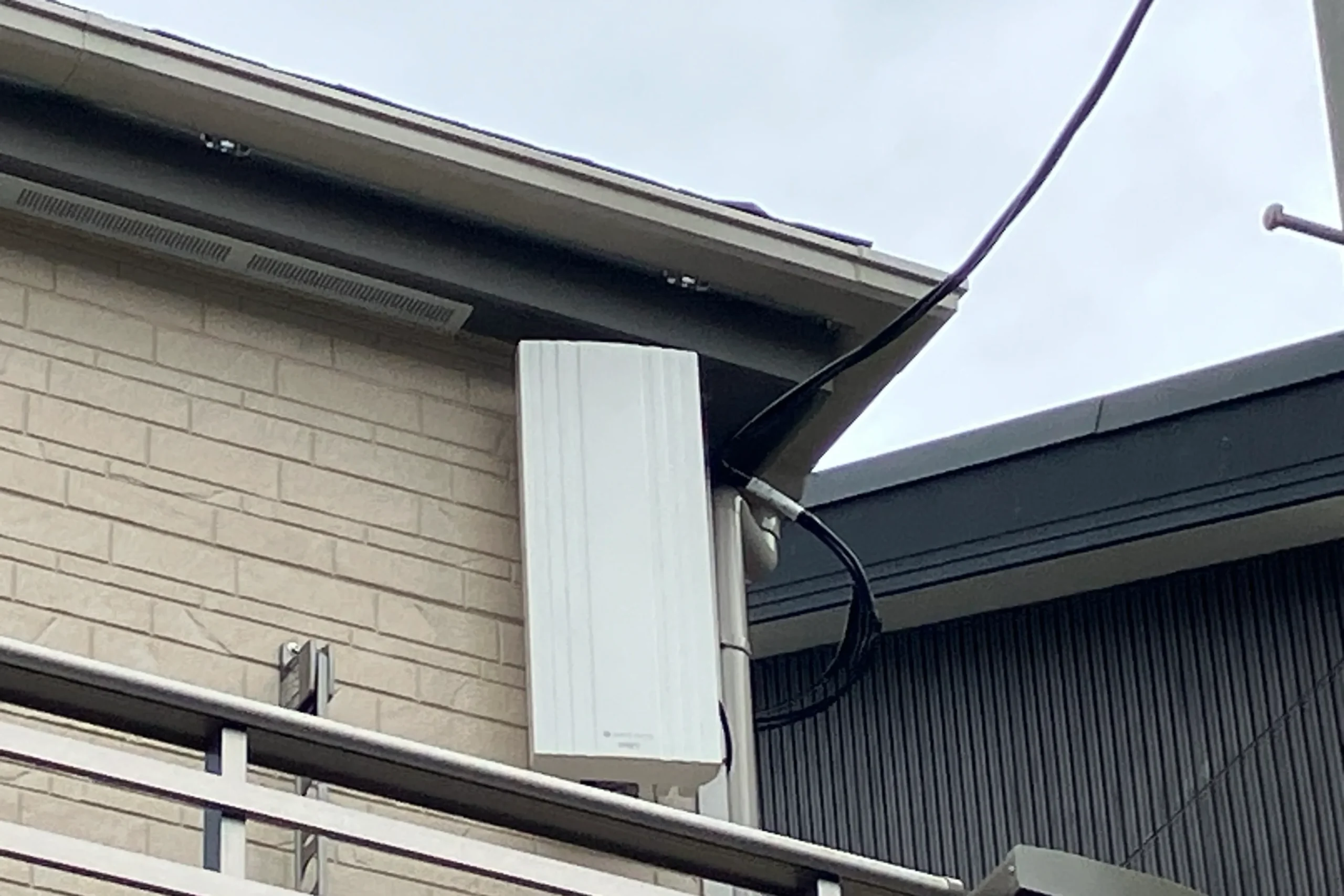 新築一戸建て住宅の白い外壁になじむように設置された、スタイリッシュな長方形の平面デザインアンテナ