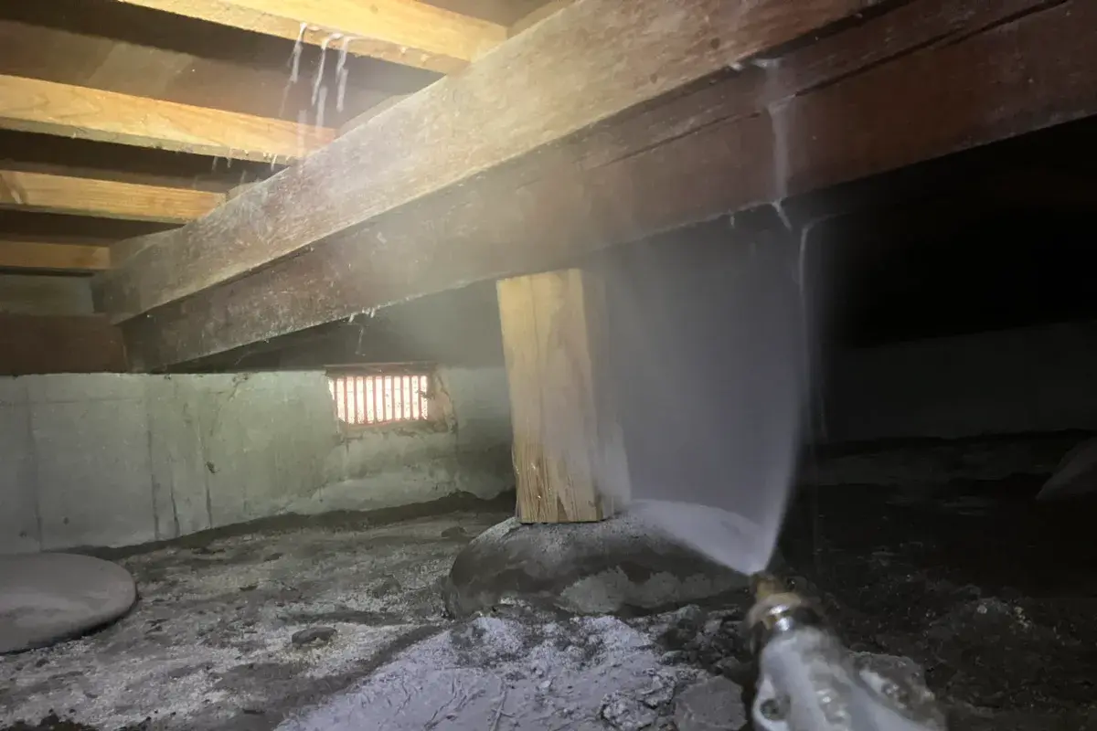 床下の土壌と木部へシロアリ予防薬剤を噴霧散布している様子