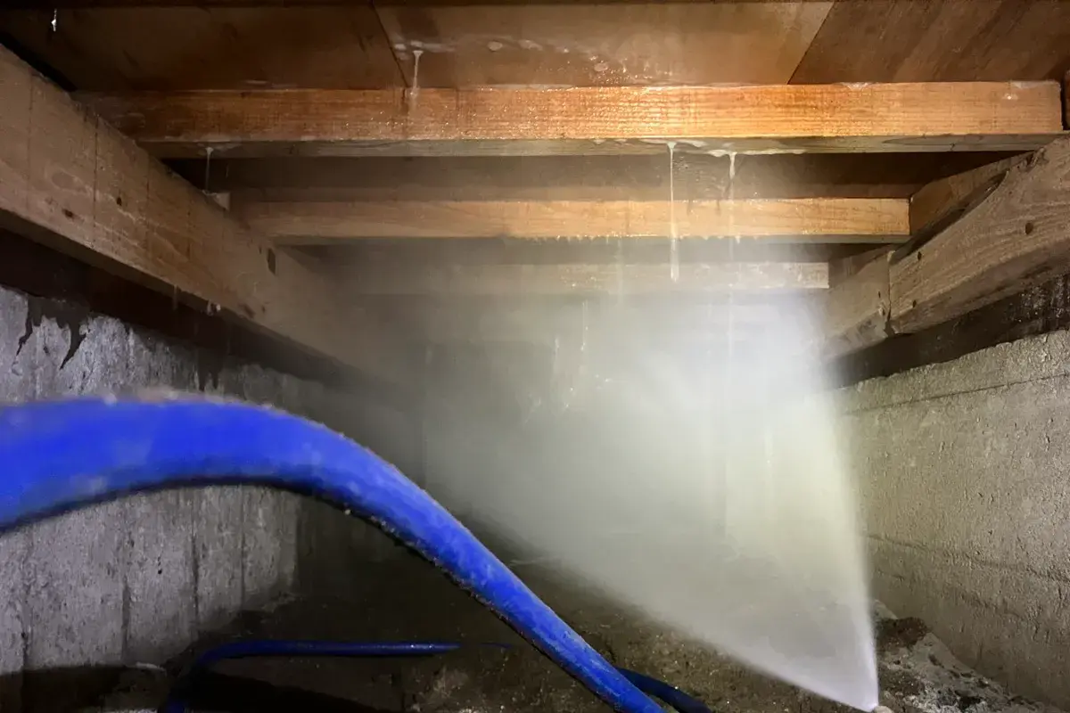 床下の土壌に薬剤を浸透させ、シロアリの侵入経路を遮断している作業中の様子