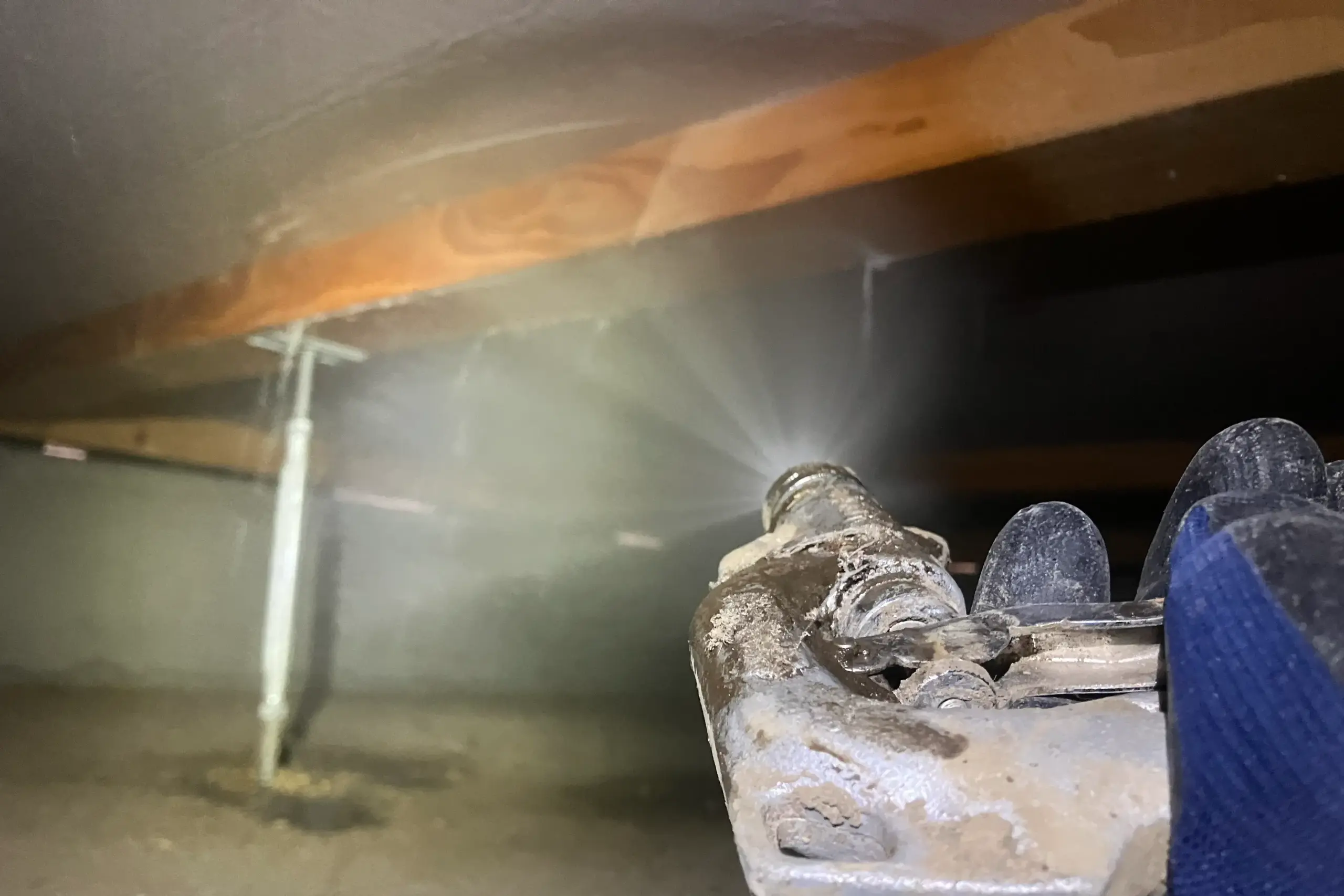 床下で専門ノズルを使い、木材に向けてシロアリ予防薬剤を噴霧・散布している作業中の様子